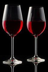 Two glasses of red wine on a glossy table.