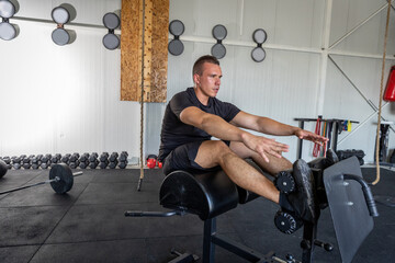 Man doing crunches exercise in the gym on a special bench