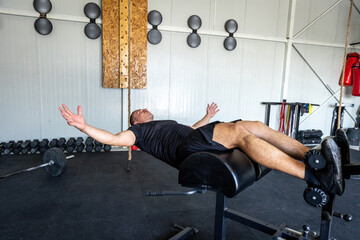Man doing crunches exercise in the gym on a special bench