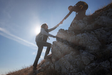 Help and assistance concept. Silhouettes of two people climbing mountains and helping against the...