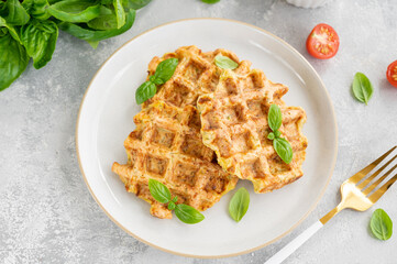 Homemade zucchini cheese waffles with sour cream and fresh basil on a plate on a gray concrete background. Vegetarian dish. Copy space.