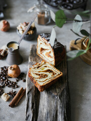 Sweet walnut roll on a gray background and a wooden stand.