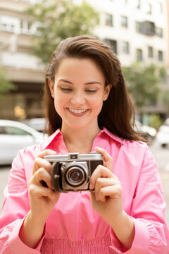 Young smiling woman taking photo on vintage camera