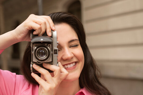 Young smiling woman taking photo on vintage camera