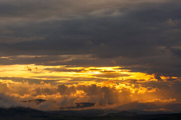 Sunset over mountain scenery with cloud formations