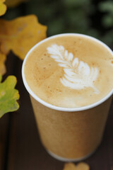 Cappuccino in a paper cup on a wooden table