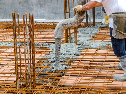 Construction worker pouring concrete into steel rebar frame