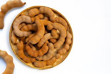 Tamarind tropical fruits in bamboo basket on white background.
