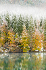 Between autumn and winter. Warm and cold reflections of snow on Lake Fusine.