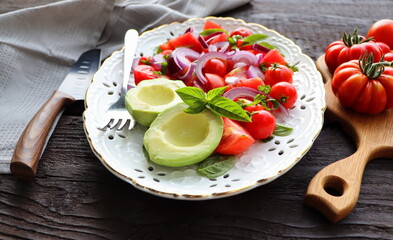 Fresh healthy avacado and tomato salad with onions on dark rusric background