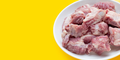 Raw pork ribs in white plate on yellow background.