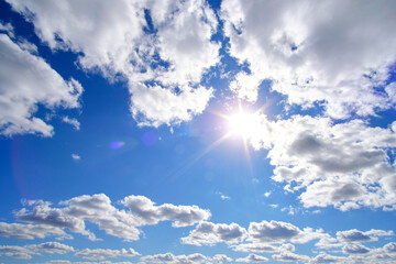 Bright, summer, sultry sun against background blue sky and white clouds.