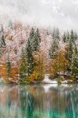 Between autumn and winter. Warm and cold reflections of snow on Lake Fusine.