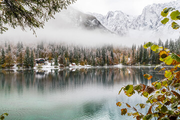 Between autumn and winter. Warm and cold reflections of snow on Lake Fusine.