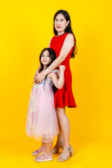 Asian mom and daughter taking portrait photo together on yellow background