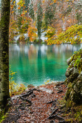 Fototapeta premium Between autumn and winter. Warm and cold reflections of snow on Lake Fusine.