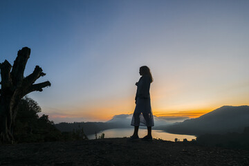 The girl meets the dawn in the mountains with a gorgeous view of the mountains and lakes