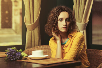 Sad young fashion woman drinking tea at restaurant