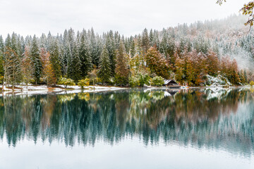 Between autumn and winter. Warm and cold reflections of snow on Lake Fusine.