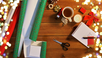 holidays, new year and christmas concept - different stuff for gifts wrapping on wooden table over festive lights