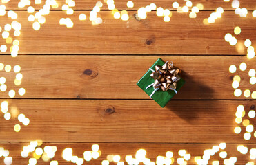 christmas, holidays and celebration concept - gift box on wooden boards from top over festive lights