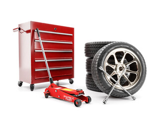 Set of tires, hydraulic car jack and workshop tool cabinet on white - obrazy, fototapety, plakaty