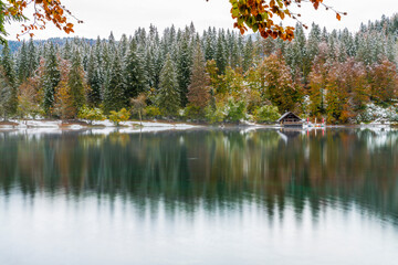 Between autumn and winter. Warm and cold reflections of snow on Lake Fusine.