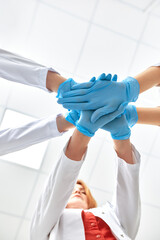 Fototapeta premium Hands in blue gloves covid, concept - creative team with hands on top of each other. Diverse team putting their hands together. One for all gesture in gloves. Covid-19 concept.
