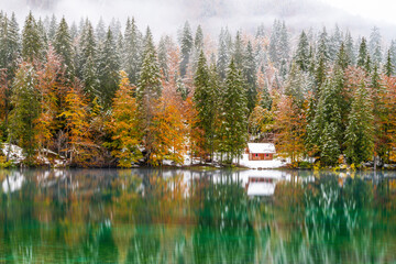 Between autumn and winter. Warm and cold reflections of snow on Lake Fusine.