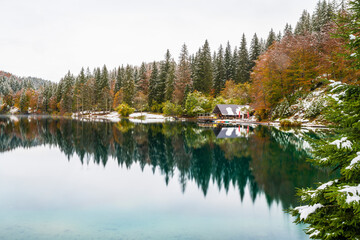 Between autumn and winter. Warm and cold reflections of snow on Lake Fusine.