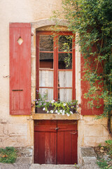 Fototapeta na wymiar Une façade d'une vieille maison. Une ancienne maison. Des volets rouges et une porte rouge. Une maison rustique
