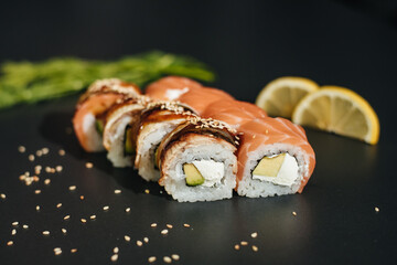 Traditional sushi - Philadelphia with salmon, avocado and cheese. Japanese cuisine. Rainbow Sushi Roll with salmon, eel, tuna, avocado, Philadelphia cream cheese, on a black background. Japanese food.