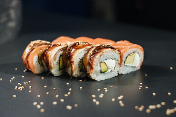 Traditional sushi - Philadelphia with salmon, avocado and cheese. Japanese cuisine. Rainbow Sushi Roll with salmon, eel, tuna, avocado, Philadelphia cream cheese on a black background. Sushi menu.
