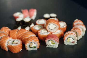 Sushi roll (Philadelphia) with salmon, smoked eel, avocado, cream cheese on black background. Sushi menu.