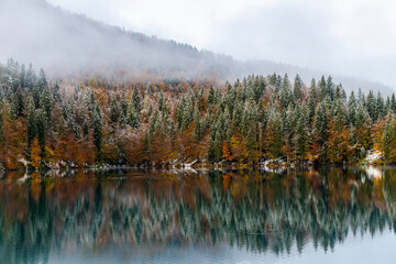 Between autumn and winter. Warm and cold reflections of snow on Lake Fusine.