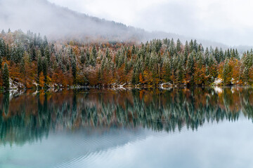 Between autumn and winter. Warm and cold reflections of snow on Lake Fusine.