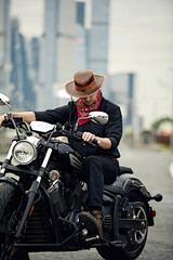 young man riding big bike ,motorcycle on city road against urban and town building scene