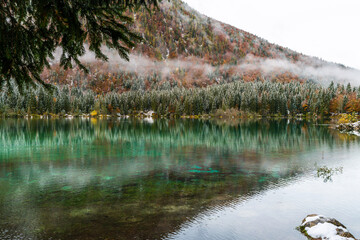 Between autumn and winter. Warm and cold reflections of snow on Lake Fusine.