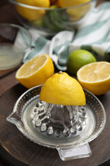 Glass squeezer and fresh lemons on wooden board