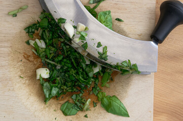 Garlic and basil are chopped using a rocking knife to chop them finely