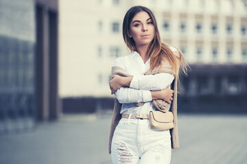 Fototapeta premium Young fashion woman in white shirt and ripped jeans
