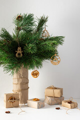 Festive Christmas table, vase with pine branches and toys, gift boxes and dried citrus fruits with star anise