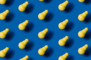 The close-up pattern of levitating neon yellow light bulbs isolated on royal blue background. Minimal electrical energy, idea, innovation and creativity concept. Flat lay.