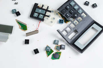 A shattered calculator on a white background. Buttons, pieces of the case, board, solar panel....