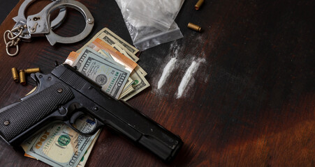 Drugs smuggling and trafficking, Handcuffs, pistol money and cocaine on wooden table background