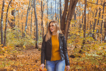 Fototapeta na wymiar Girl holds fallen leaves and walks in autumn park. Seasonal concept.
