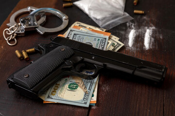 Drugs smuggling and trafficking, Handcuffs, pistol money and cocaine on wooden table background