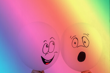 Flirting balloons in a rainbow design. Hands holding two balloons with faces drawn. Hand-drawn...