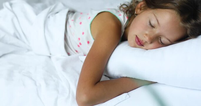Little girl sleeping on a big and cozy bed white linen in the afternoon at home, family lifestyle, comfortable pillow, bed