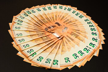 Pile of 50 real euro banknotes isolated on a black background.